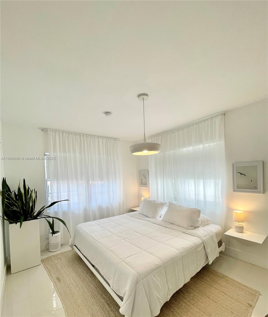1604 Drexel Avenue, Unit 209 Miami Beach, FL 33139 - Photo 6 of 9 a bedroom with a bed and a potted plant
