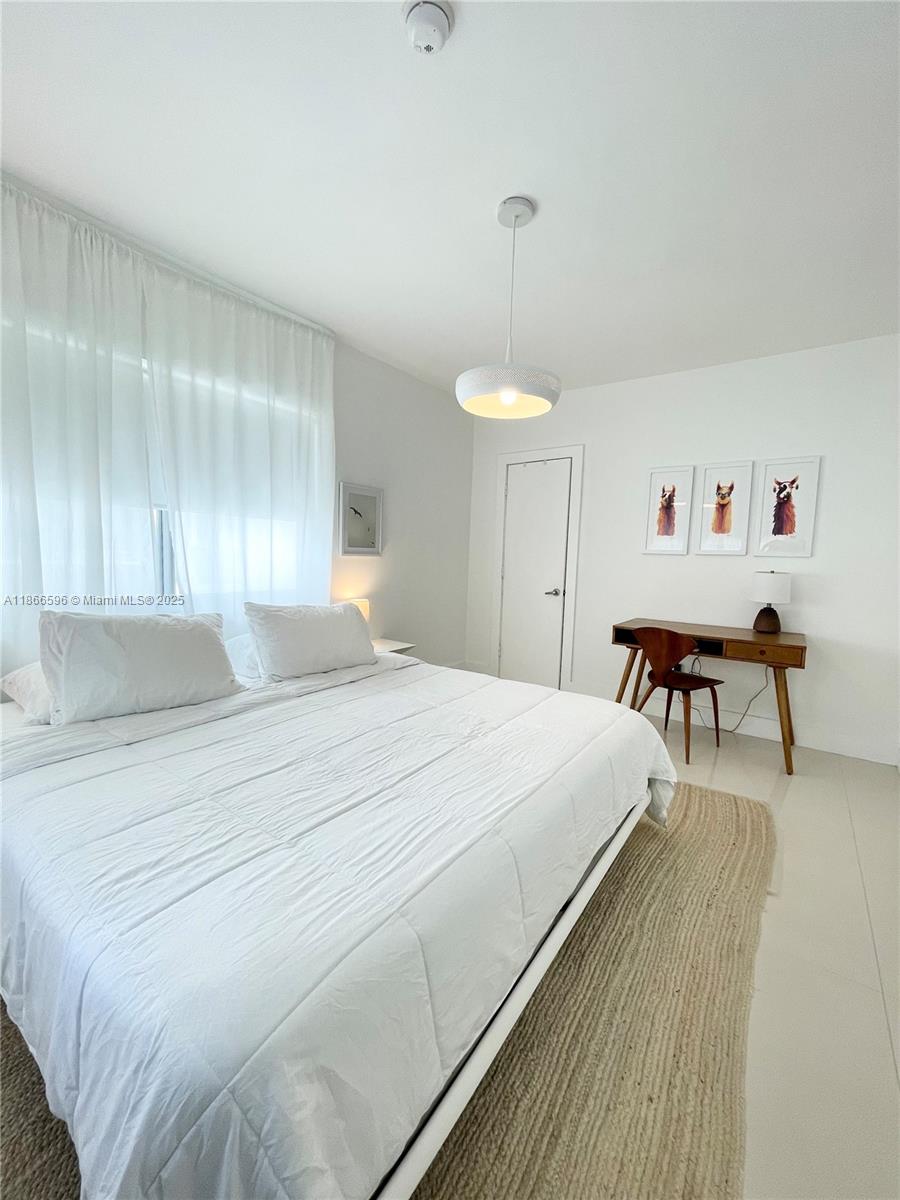 1604 Drexel Avenue, Unit 209 Miami Beach, FL 33139 - Photo 7 of 9 a spacious bedroom with a bed and a chandelier