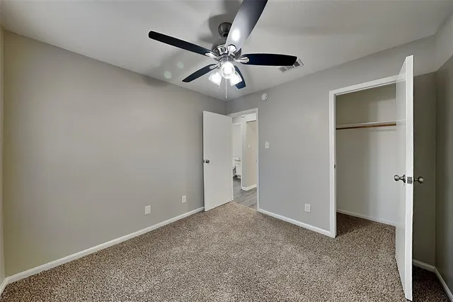 an empty room with closet and a ceiling fan