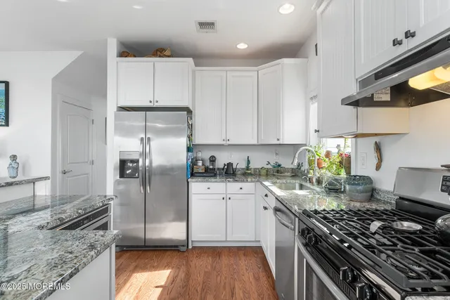 a kitchen with granite countertop a stove sink and refrigerator