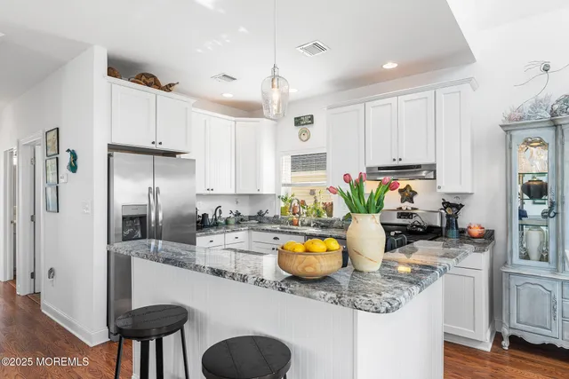 a kitchen with stainless steel appliances granite countertop a sink a stove a refrigerator cabinets and living room view