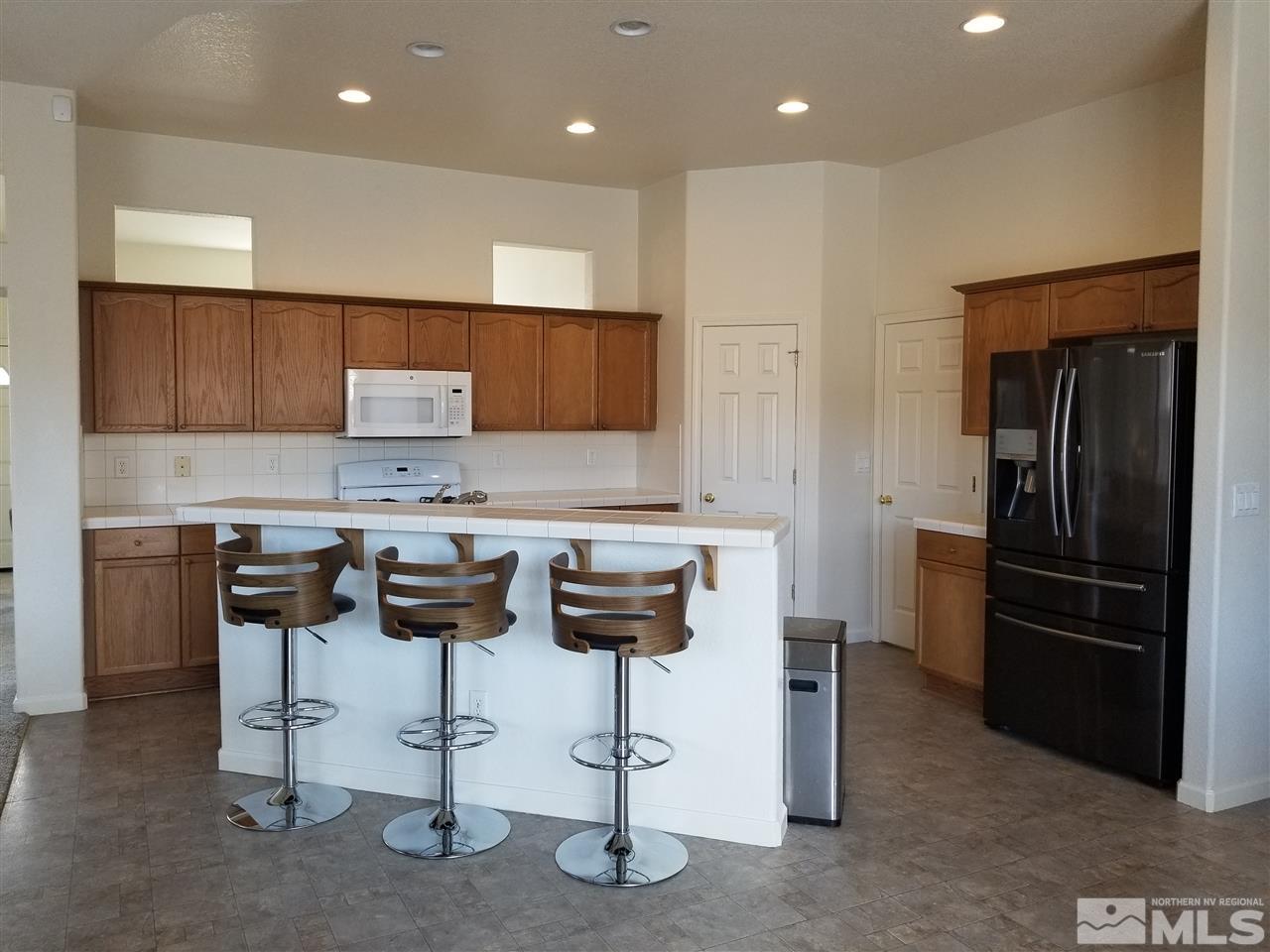 9625 Glen Ridge Drive Reno, NV 89521 - Photo 9 of 23 a kitchen with stainless steel appliances kitchen island granite countertop a refrigerator and a stove top oven