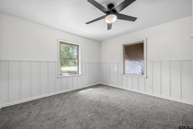 an empty room with windows and fan