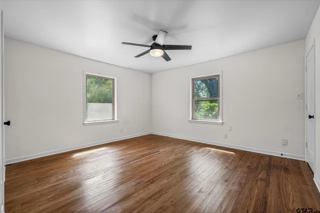 a view of empty room with wooden floor and fan