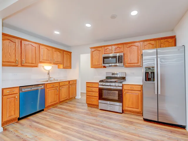 a kitchen with stainless steel appliances granite countertop a stove a sink dishwasher a refrigerator and a microwave oven with wooden floor