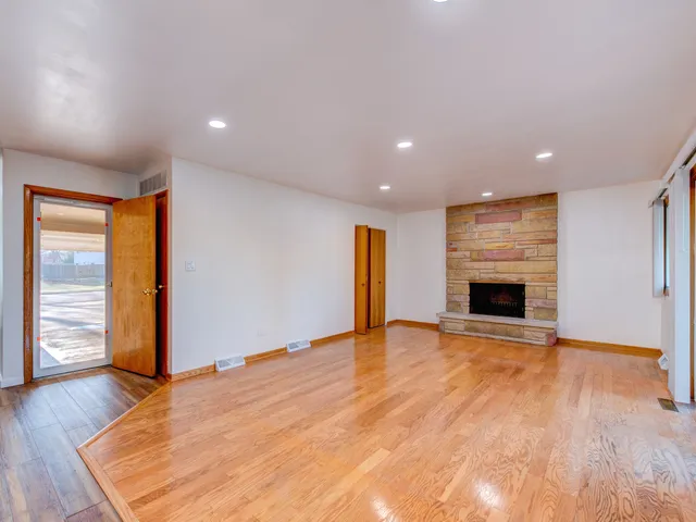 an empty room with wooden floor fireplace and windows