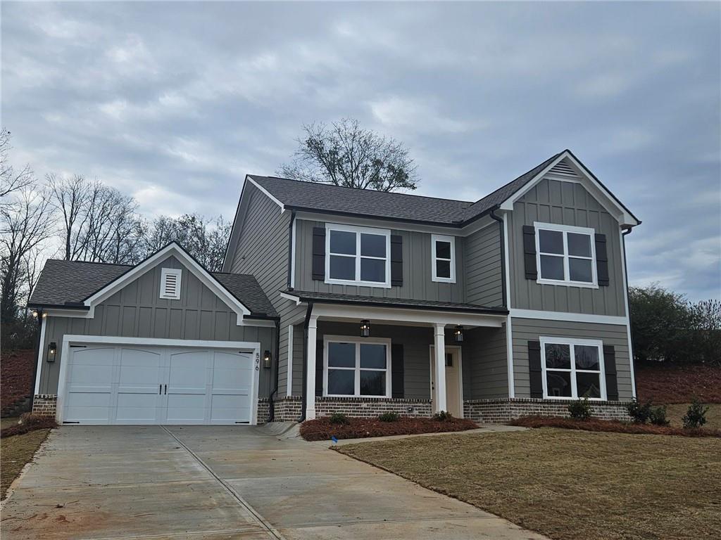 596 Calgary Downs Drive Winder, GA 30680 - Photo 2 of 3 a front view of a house with a garden and trees