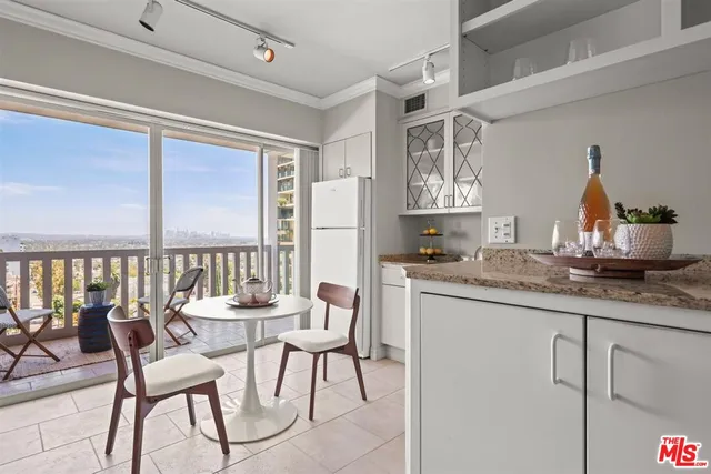 a dining room with kitchen island furniture a large window and a potted plant