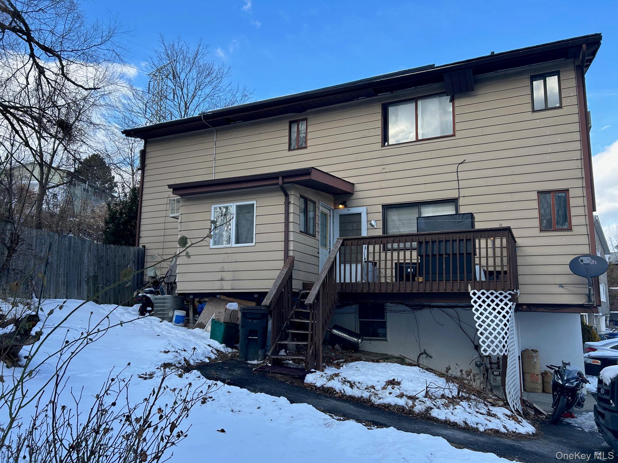 Snow covered rear of property featuring a wooden deck