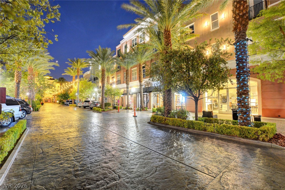48 Jasmine Point Street Henderson, NV 89074 - Photo 3 of 62 Illuminated palm trees line the street, creating an inviting atmosphere within this vibrant urban setting.