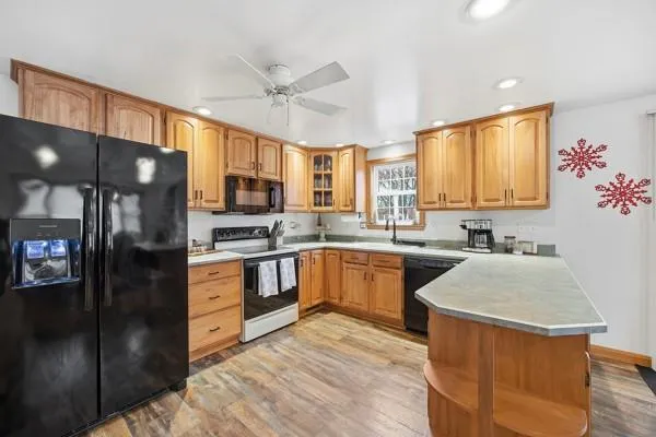 a kitchen with stainless steel appliances granite countertop a refrigerator a sink dishwasher a stove with wooden cabinets and floor