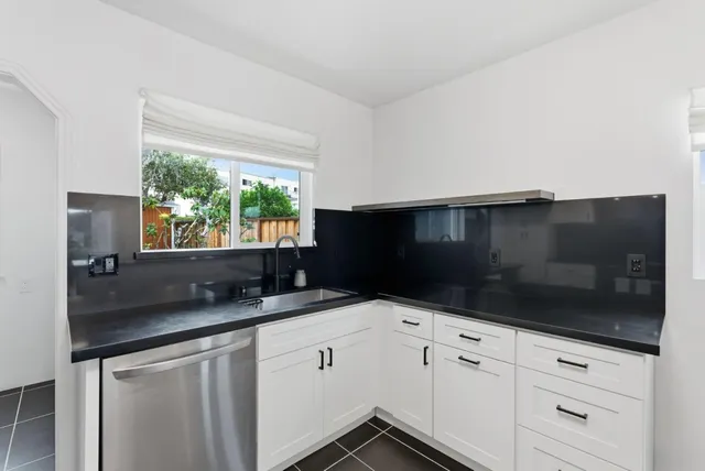 a kitchen with granite countertop white cabinets and black appliances