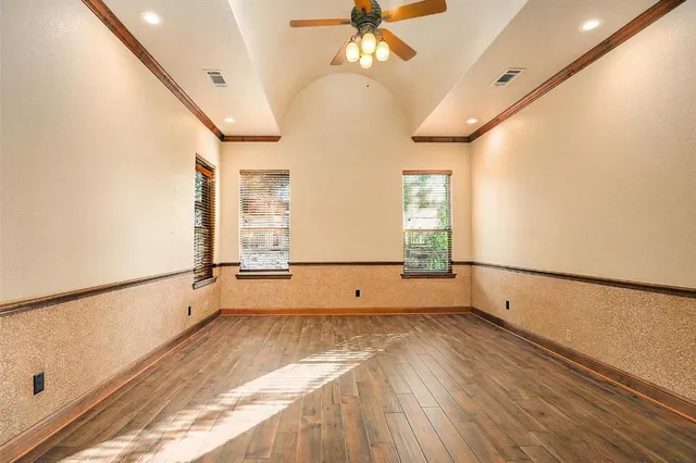 a view of empty room with wooden floor and fan
