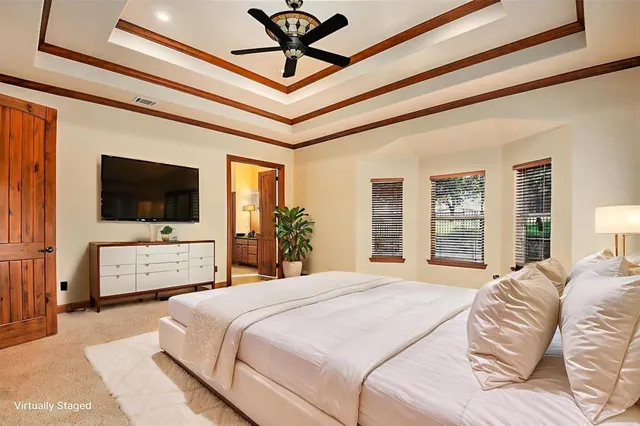 a bedroom with a bed a tv on the wall and a large window