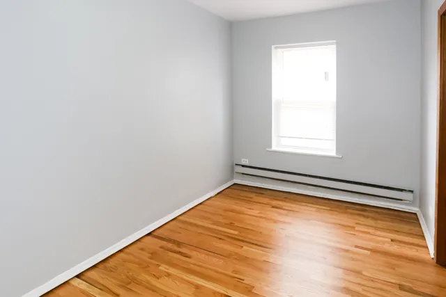 an empty room with wooden floor and a window