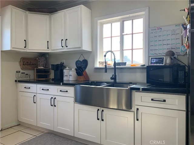 a kitchen with white cabinets and window