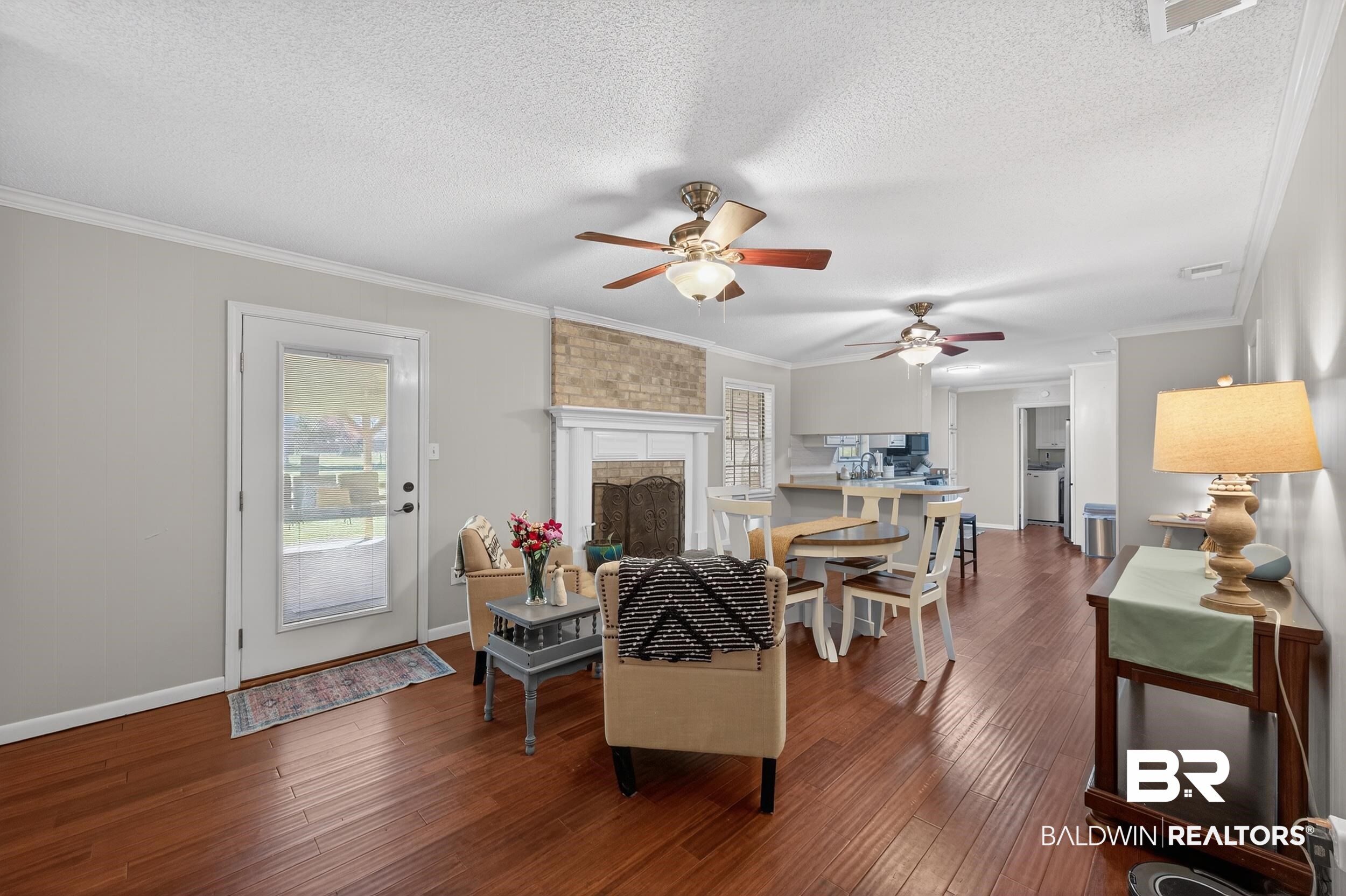 46006 Pecan Lane Bay Minette, AL 36507 - Photo 17 of 40 Living room with wood-type flooring, ornamental molding, a textured ceiling, a brick fireplace, and ceiling fan