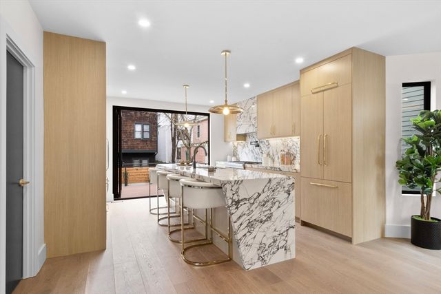 a kitchen with stainless steel appliances kitchen island granite countertop a sink a stove a dining table and chairs with wooden floor