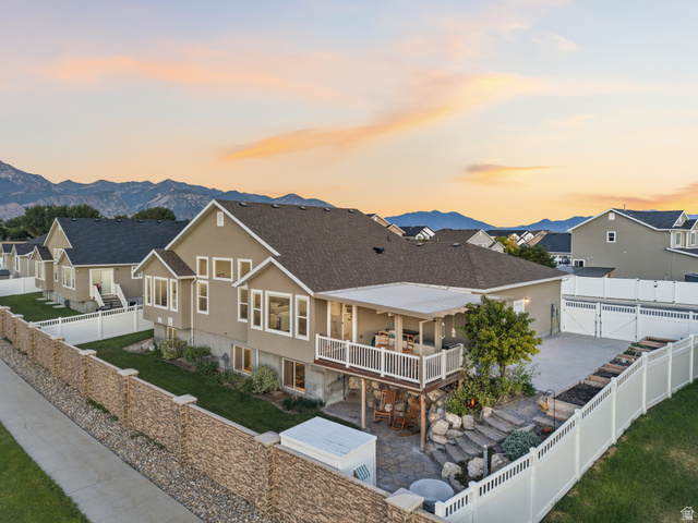 7 Sterling Loop Vineyard, UT 84059 - Photo 41 of 43 Rear exterior featuring an upper-level covered balcony, lower-level patio with stone steps, a manicured lawn, and mountain scenery