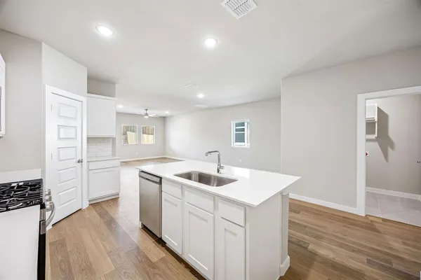 a kitchen that has a sink a stove and wooden floor