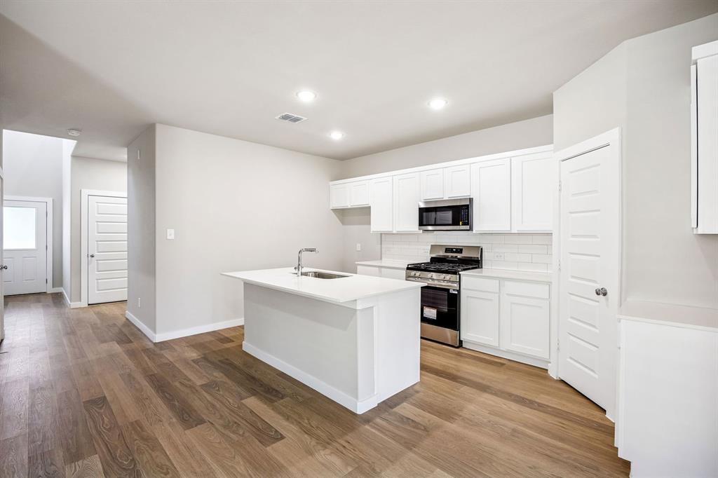 144 Millwood Road Lavon, TX 75166 - Photo 7 of 37 a kitchen with stainless steel appliances white cabinets a sink a stove a microwave and a refrigerator