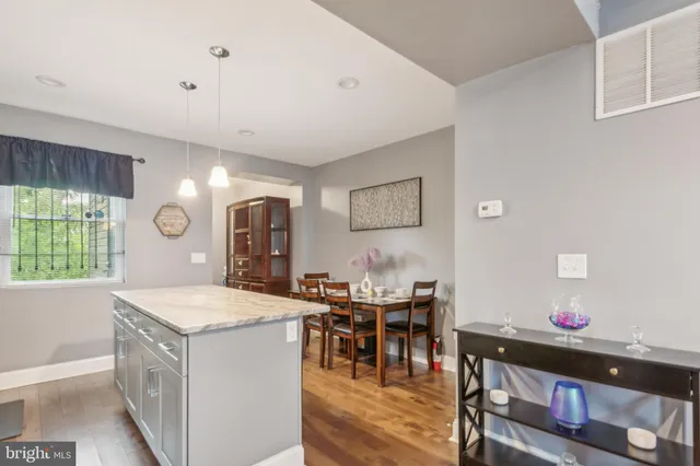 a hall with kitchen island a stove a dining table and chairs with wooden floor