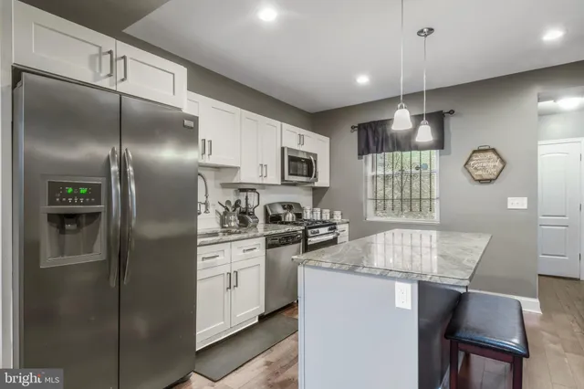 a kitchen with stainless steel appliances granite countertop a refrigerator a stove a sink dishwasher and a refrigerator with wooden floor