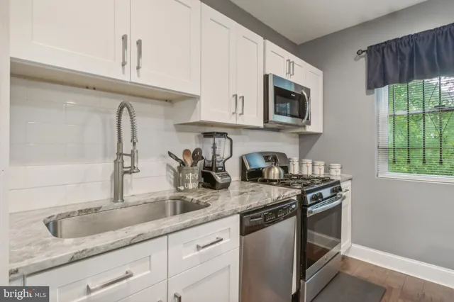 a kitchen with granite countertop stainless steel appliances a sink a stove and a microwave