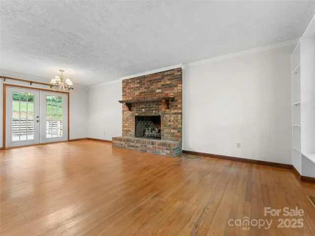 an empty room with wooden floor fireplace and windows