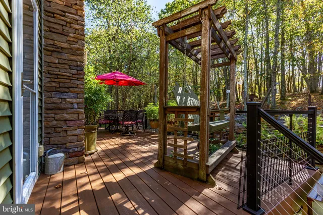 a view of a patio with table and chairs under an umbrella with large trees