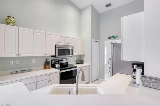 a kitchen with white cabinets and stainless steel appliances