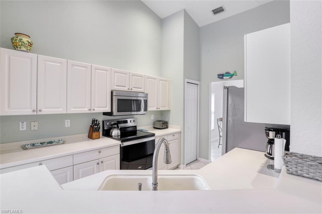 5630 Sherborn Drive, Unit 202 Naples, FL 34110 - Photo 5 of 18 a kitchen with white cabinets and stainless steel appliances
