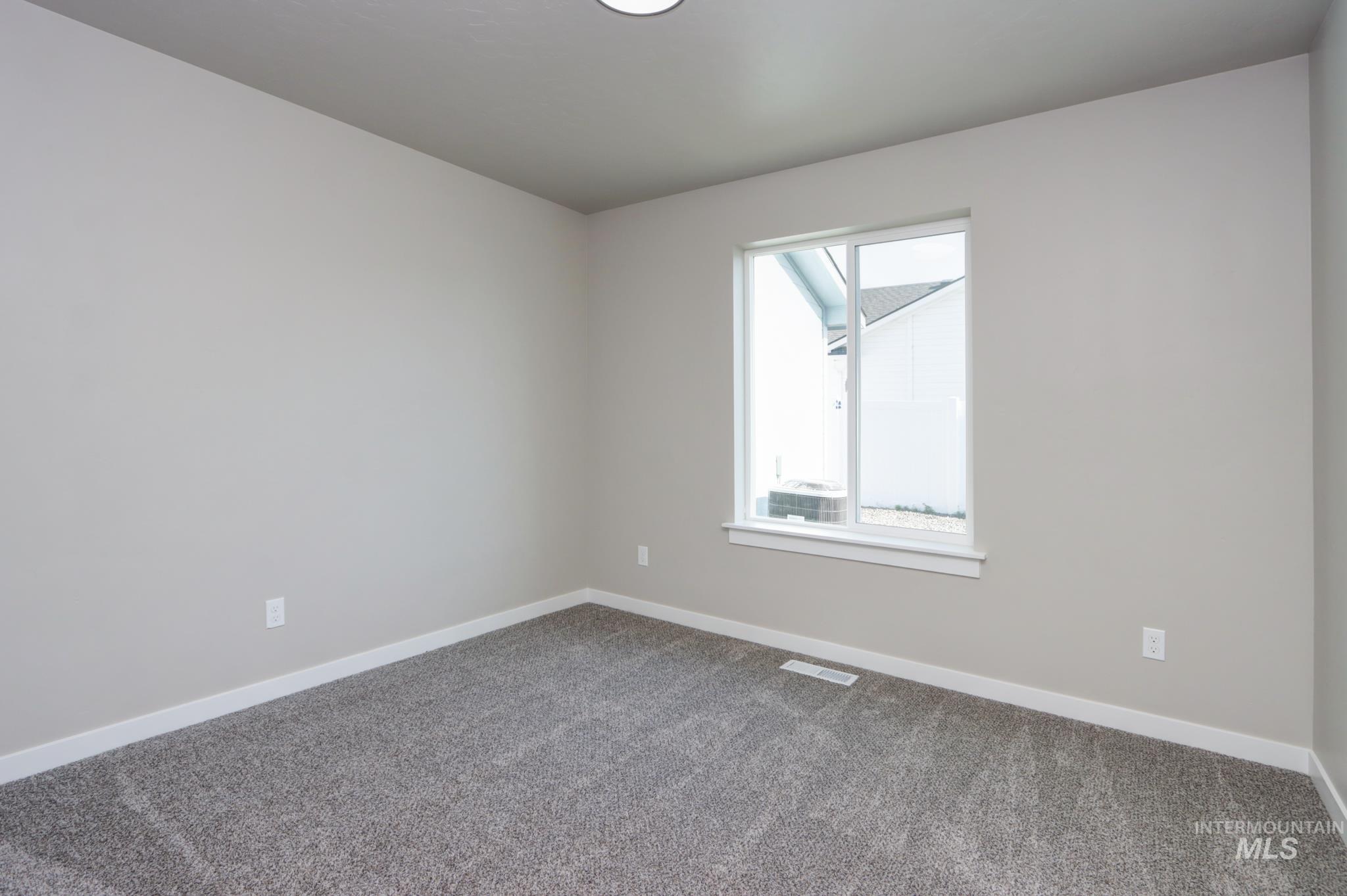 848 North 5th Street Nyssa, OR 97913 - Photo 35 of 49 Neutral paint finishes throughout this room, featuring a white window frame, white baseboards, a flush-mount ceiling light, and gray carpeting