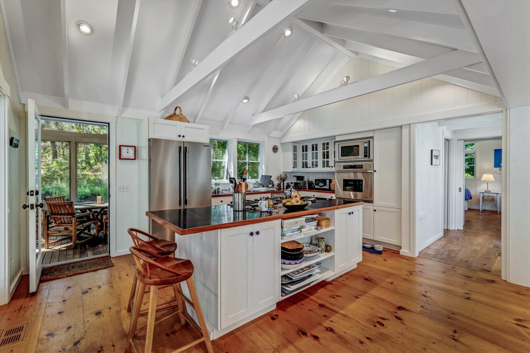 16 Tom's Hill Road Truro, MA 02666 - Photo 5 of 27 a kitchen with stainless steel appliances a stove top oven a refrigerator a dining table and chairs with wooden floor