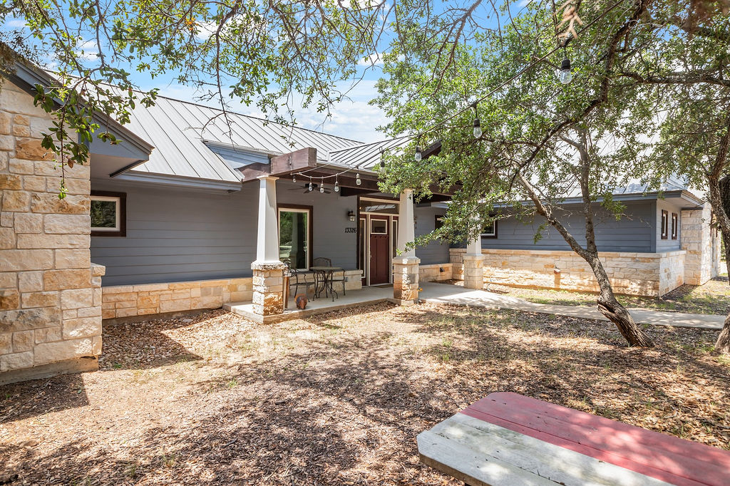 13326 Trautwein Road Austin, TX 78737 - Photo 35 of 38 Back of property with stone siding, a standing seam roof, a patio area, and metal roof