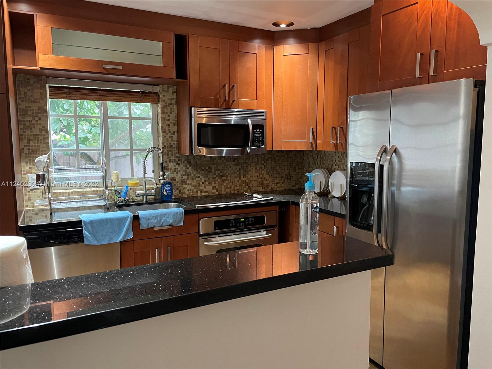 4220 Southwest 13th Street, Unit 4220 Miami, FL 33134 - Photo 7 of 14 a kitchen with stainless steel appliances granite countertop a refrigerator a stove and a sink with wooden floor