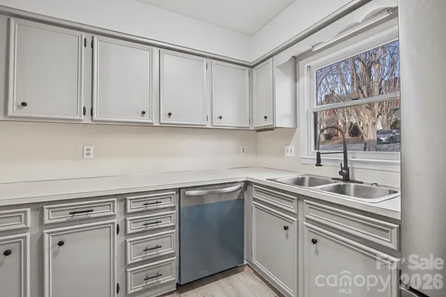 a kitchen with stainless steel appliances granite countertop a sink and dishwasher with white cabinets