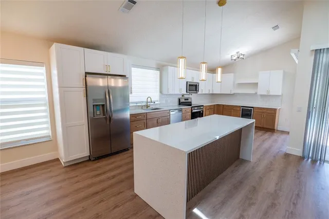 a large kitchen with stainless steel appliances a refrigerator a sink dishwasher a stove and white countertops with wooden floor