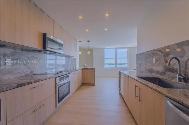 a large kitchen with stainless steel appliances granite countertop a sink and cabinets