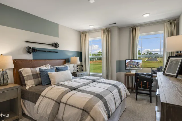 a bedroom with a bed a computer on the desk and a dresser