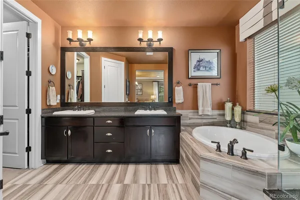 a bathroom with a tub a double vanity sink and a large mirror