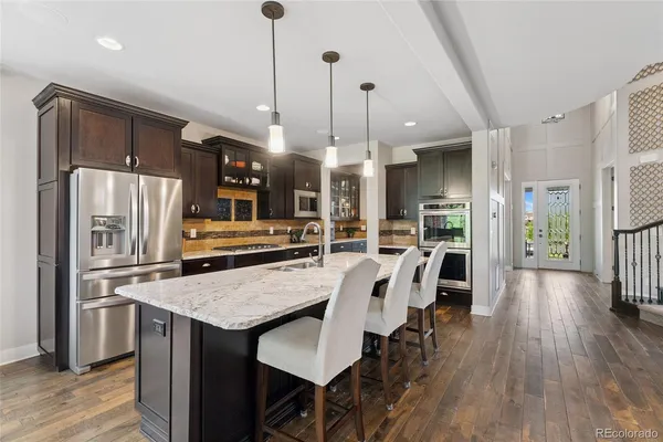 a kitchen with stainless steel appliances a dining table chairs stove refrigerator and wooden floor