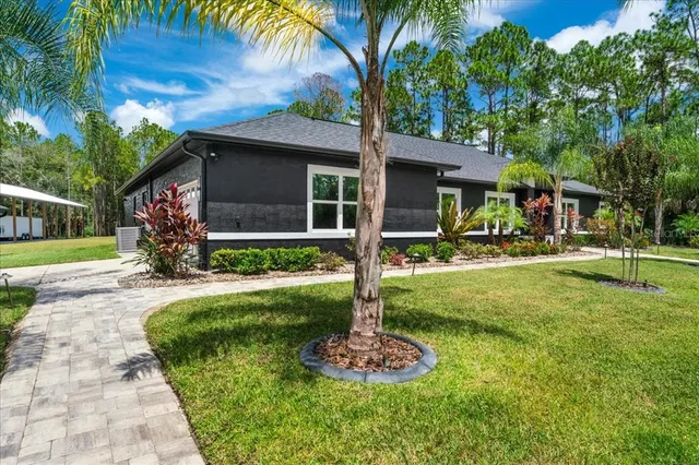 a view of a brick house next to a yard with big trees