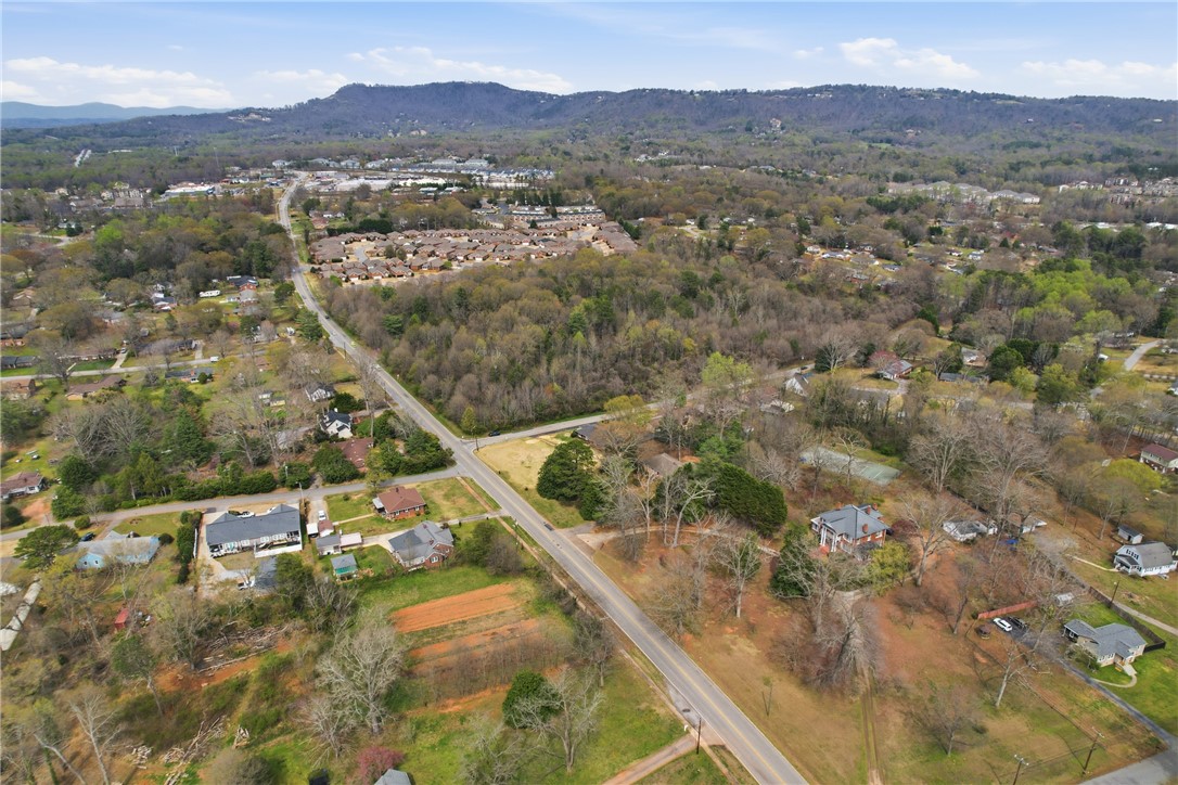 4304 Old Buncombe Road Greenville, SC 29617 - Photo 46 of 49 An aerial perspective showcases a residential area nestled among lush trees and distant mountains.