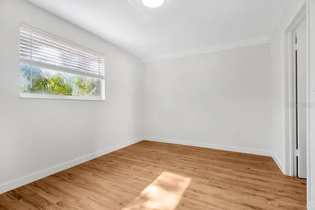 a view of an empty room with wooden floor and a window
