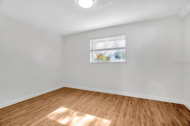 an empty room with a window and wooden floor