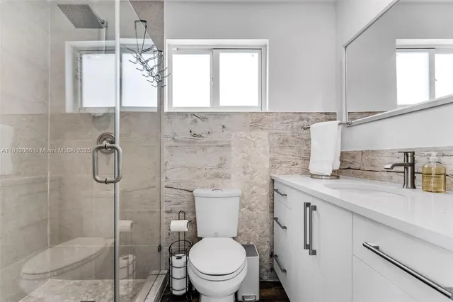 a bathroom with a granite countertop sink a toilet and shower