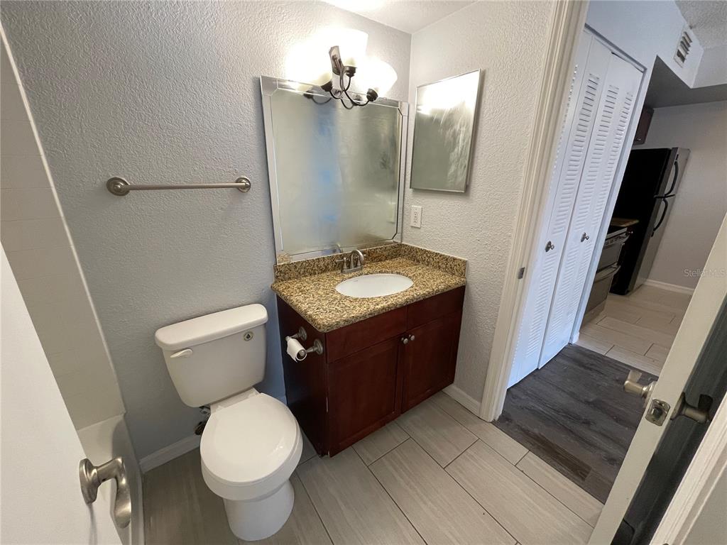 5128 Conroy Road, Unit 13 Orlando, FL 32811 - Photo 16 of 25 a bathroom with a granite countertop toilet sink and mirror