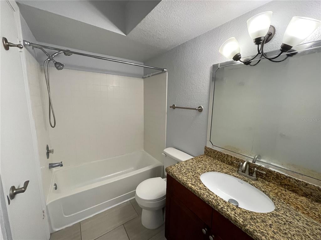5128 Conroy Road, Unit 13 Orlando, FL 32811 - Photo 17 of 25 a bathroom with a granite countertop sink toilet and shower