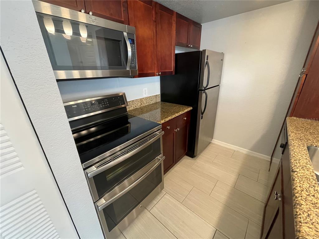 5128 Conroy Road, Unit 13 Orlando, FL 32811 - Photo 6 of 25 a kitchen with wooden cabinets and stainless steel appliances